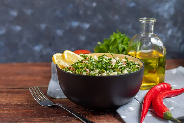 Tabbouleh salade in een ronde plaat op een houten ondergrond. — Stockfoto