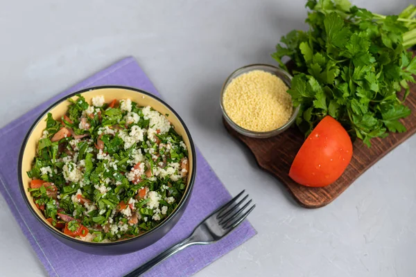 Tabbouleh salát v kulatém talíři na světle šedém pozadí pod betonem. — Stock fotografie