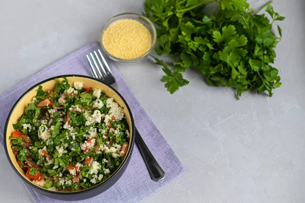 Tabbouleh salade in een ronde plaat op een lichtgrijze achtergrond onder beton. — Stockfoto