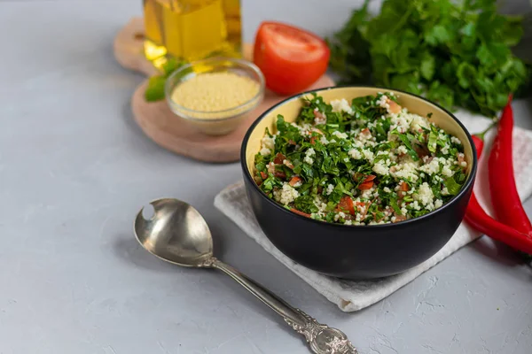 Tabbouleh salade in een ronde plaat op een lichtgrijze achtergrond onder beton. — Stockfoto
