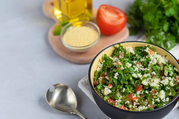 Tabbouleh salade in een ronde plaat op een lichtgrijze achtergrond onder beton. — Stockfoto