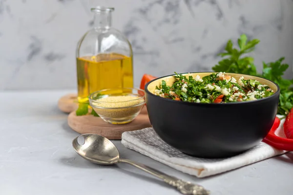 Tabbouleh salade in een ronde plaat op een lichtgrijze achtergrond onder beton. — Stockfoto