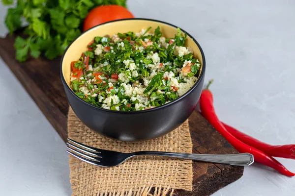 Salată de tabbouleh într-o placă rotundă pe un fundal gri deschis sub beton . — Fotografie, imagine de stoc