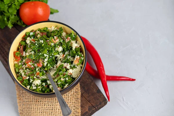 Tabbouleh salade in een ronde plaat op een lichtgrijze achtergrond onder beton. — Stockfoto