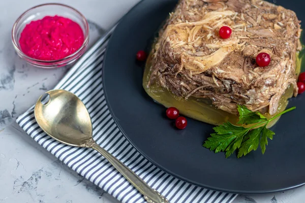 Jalea con carne, cerdo y pollo, aspic. Plato tradicional ruso, servido en un plato oscuro junto al rábano picante en un tazón . — Foto de Stock