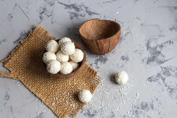 Caramelos en copos de coco y coco fresco con semillas de lino sobre un fondo de piedra gris. Bolas de energía . — Foto de Stock