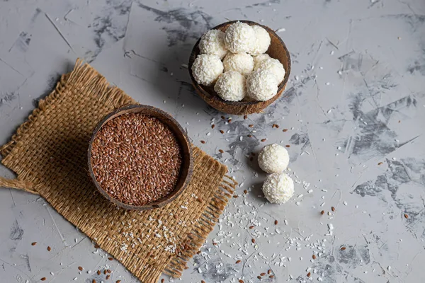 Caramelos en copos de coco y coco fresco con semillas de lino sobre un fondo de piedra gris. Bolas de energía . — Foto de Stock