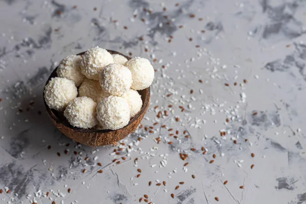 Caramelos en copos de coco y coco fresco con semillas de lino sobre un fondo de piedra gris. Bolas de energía . — Foto de Stock