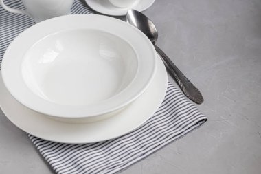 Akşam yemeği planı. Gri bir peçeteye servis yapmak çok güzel. Çorba ya da meze için bir tabak. Açık gri arkaplan ve beyaz plakalar.