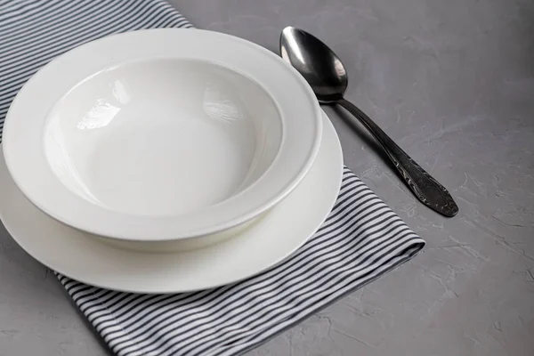 Aménagement des repas. Magnifique service sur une serviette en lin gris. Une assiette pour la soupe ou un plat d'accompagnement. Fond gris clair et plaques blanches . — Photo