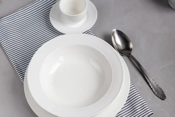 Aménagement des repas. Magnifique service sur une serviette en lin gris. Une assiette pour la soupe ou un plat d'accompagnement. Fond gris clair et plaques blanches . — Photo