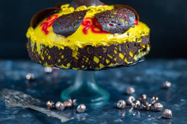 Sarı tereyağlı krema sürülmüş ve çikolata figürleriyle süslenmiş sünger kek. Mavi bir masa örtüsü ve mavi bir arkaplan üzerinde