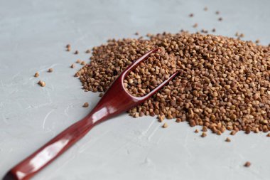 Karabuğday, orta pişmiş. Yulaf lapası yapmak için ölçülmüş. Betonun altındaki gri arka planda.