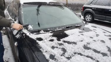 Cleaning the car that was snowing. Winter cold morning, black car in the parking lot.