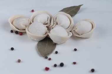 Hafif arka planda birkaç çiğ, donmuş hamur köftesi. Yakınlarda defne yaprakları ve tüm baharat çekirdekleri var. Yukarıdan görüntüle.