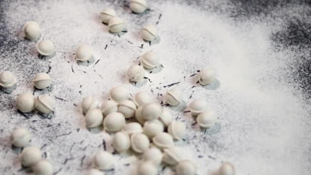 小麦粉がテーブルに注ぐ 生地製品を作るために ミニ餃子は立ち往生していません 餃子は小麦粉に落ちる 暗色の大理石の背景 白い小麦粉 — ストック動画