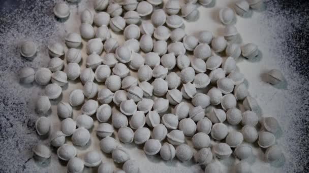 La farine se déverse sur la table. Afin de fabriquer des produits à base de pâte, les mini-boulettes ne sont pas collées. Les boulettes tombent dans la farine. Fond marbré foncé. Farine blanche .