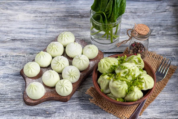 Boiled khinkali made of dough with spinach. Garnished with Red Chilli, Dill and Parsley. On a light gray background under — Stock Photo, Image