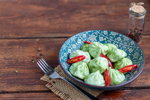 Khinkali rebus yang terbuat dari adonan dengan bayam. Dihiasi dengan Red Chilli, Dill dan Parsley. Pada latar belakang kayu . — Stok Foto