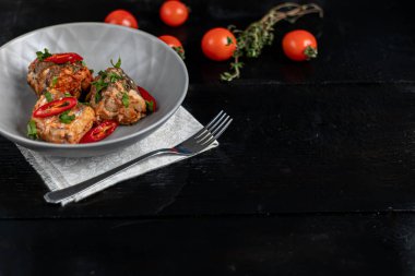 Morina filetosu ya da gri tabakta diğer balıklar. Domates ve soğanla pişirilmiş. Bezelyeler yeşil yapraklar ve fidanlardan çıkan mikroyeşillerle serpiştirilir. Siyah ahşap arka planda.