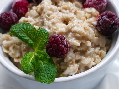 Yulaf ezmesi, fındık ve meyvelerden oluşan kahvaltı. Kivi ahududu böğürtlen, nar, nane şekeri bir tabak süsler. Sağlıklı beslenme