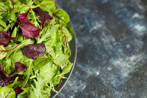 Mélange de jeunes laitues vertes, d'épinards, de roquette et de jeunes betteraves. Une alimentation saine. Petit déjeuner végétarien. Sur un fond sombre . — Photo