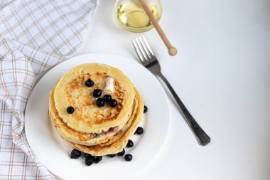 Ahududu, böğürtlen ve yabanmersinli bir yığın lezzetli krep. Hafif bir arkaplanda. Üzerine şekerleme ve süsleme serpilmiş.