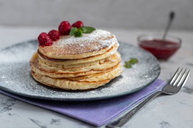 Ahududu, böğürtlen ve yabanmersinli bir yığın lezzetli krep. Hafif bir arkaplanda. Üzerine şekerleme ve süsleme serpilmiş.