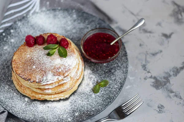 Una pila de deliciosos panqueques con frambuesas, moras y arándanos. Sobre un fondo claro. Espolvoreado con azúcar glaseado y decorado — Foto de Stock