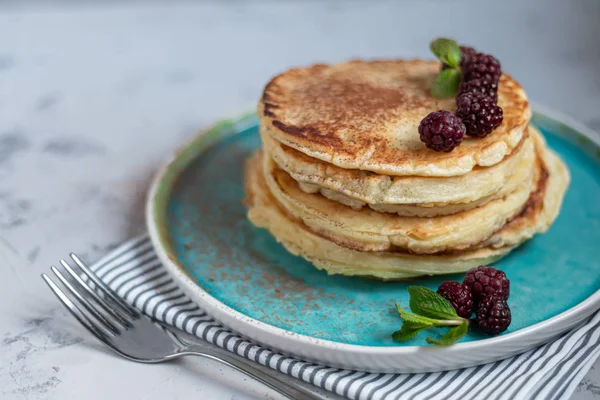 Una pila de deliciosos panqueques con frambuesas, moras y arándanos. Sobre un fondo claro. Espolvoreado con azúcar glaseado y decorado — Foto de Stock