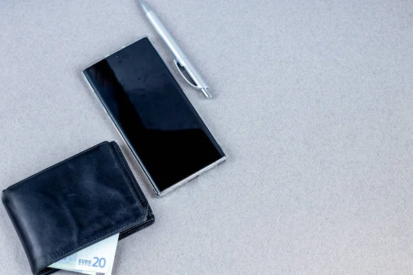 Üzerinde gerekli eşyalar olan gri bir yüzey. Kalemle günlük, Samsung telefonu. Bir fincan beyaz kahve. Kopyalama alanı olan üst görünüm,