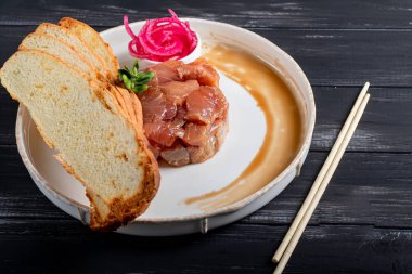 Salamura edilmiş gümüş sazan, doğranmış soğan, şarap sirkesinin yanında, kızarmış ekmek. Mikro yeşille süslenmiş. Ahşap bir arka planda.