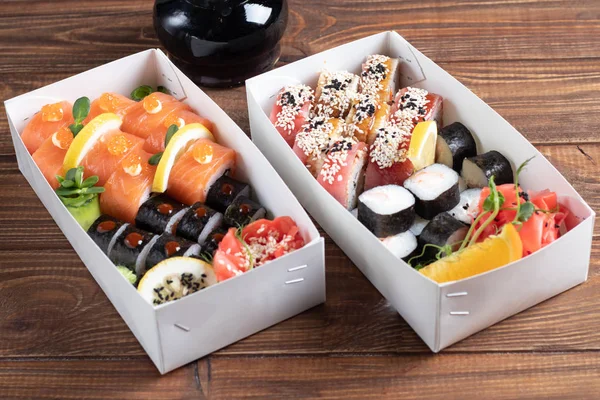 Bir kutu suşi Nigiri, Uramaki California, Philadelphia, siyah bir taş tabakta. Ahşap arka planda beyaz bir nakliye kutusunda suşi menüsü..