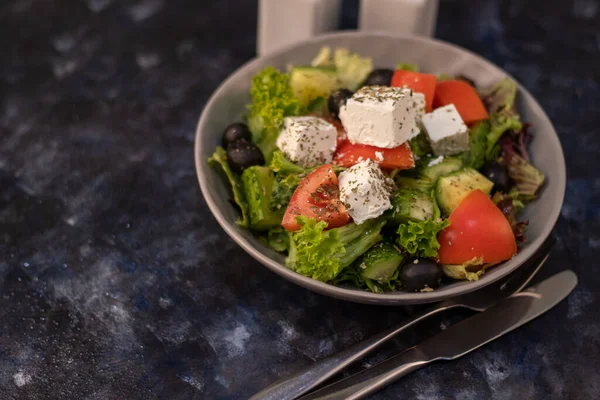 Greek vegetable salad. It consists of tomatoes, olives, feta cheese, herbs, cucumbers and red onions. On a wooden background. — 图库照片