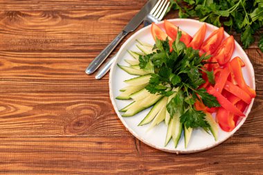 Fresh vegetables and herbs. Ingredients for the salad. Cucumbers tomatoes Bulgarian pepper with spinach, parsley. On a wooden background.