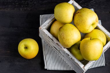 Golden apples are collected in a wooden, light, natural, environmentally friendly box. Harvesting. Delicacy for guests, vegetarian food, healthy food.