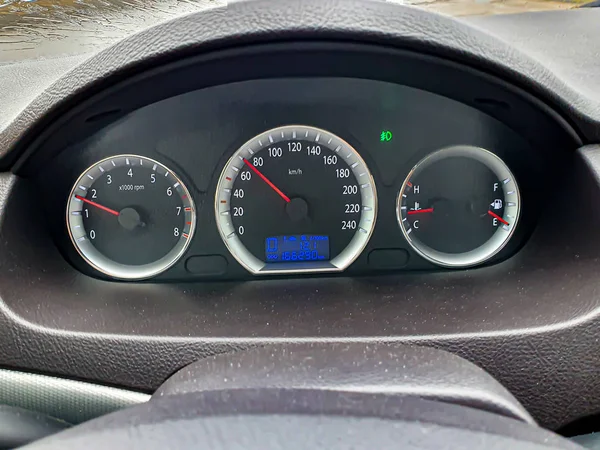 Car dashboard. Speedometer, circular tachometer, oil and fuel level, mileage. Outside the window it is raining, the wipers are visible. — 스톡 사진