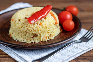 Rice with vegetables. Vegetarian dish. Mushrooms and carrots, onions, spices, hot chili peppers and garlic. Black pepper and zira. Cooking in olive oil. Healthy diet. On a wooden background.