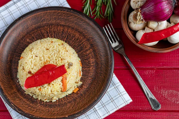 Rice with vegetables. Vegetarian dish. Mushrooms and carrots, onions, spices, hot chili peppers and garlic. Black pepper and zira. Cooking in olive oil. Healthy diet. On a wooden background. — 스톡 사진