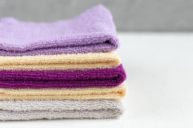 Terry güzellik ve sağlık için havlu. Beyaz arka planda çok renkli havlular yığını var. Yaşam tarzı, ev işi..