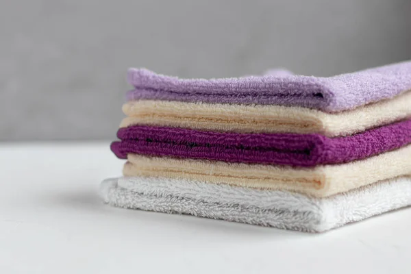 Frotteetücher für Schönheit und Gesundheit. Auf weißem Hintergrund liegt ein Stapel mehrfarbiger Handtücher. Lebensstil, Hausarbeit. — Stockfoto