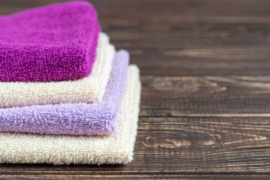 Terry güzellik ve sağlık için havlu. Bir yığın çok renkli havlu ahşap bir arka planda yatıyor. Yaşam tarzı, ev işi resmi.
