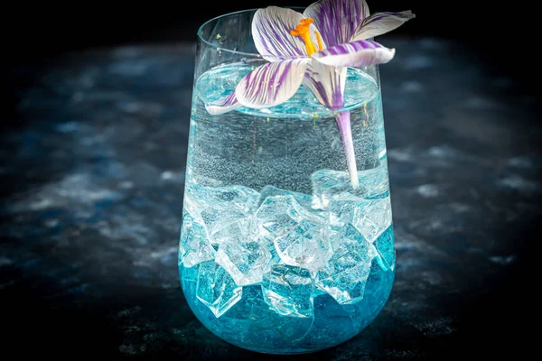 Cocktail with blue liquor and ice. Celebratory drink for women\'s day, birthday, easter. On a dark background. Copy space