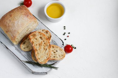 Biberiyeli ciabatta, zeytinyağı ve ahşap bir tahtada kiraz domatesleri. Beyaz arka planda. Boşluğu kopyala