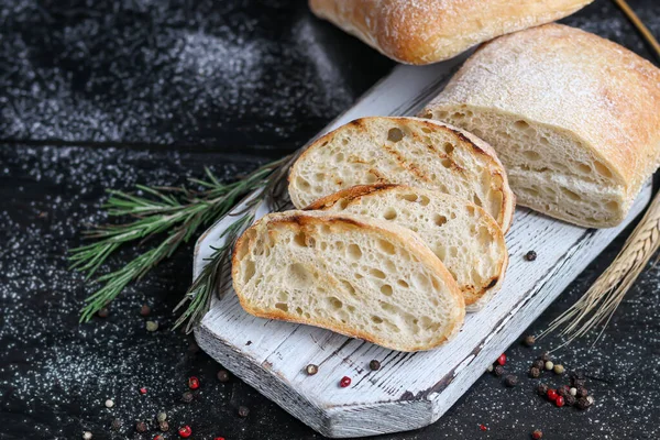 Biberiyeli ciabatta, zeytinyağı ve ahşap bir tahtada kiraz domatesleri. Karanlık bir arka planda. Boşluğu kopyala