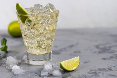 Bardaklar buz ve soğuk yeşil çayla doludur. Limon dilimleri ve bir tutam nane ile süslenmiş. Hafif bir arkaplanda. Boşluğu kopyala