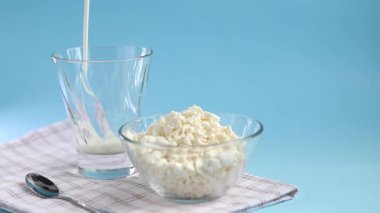 Şeffaf bir kâse içinde taze süzme peynir ve mavi arka planda bir bardak kefir. Mayalanmış yiyecekler. Sağlık için iyi bir bakteri. Boşluğu kopyala