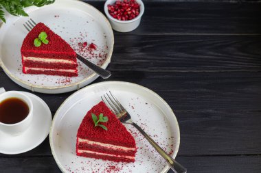 İki beyaz tabakta kırmızı kadife kek, iki porsiyon. Siyah bir arka planda. Doğum günü, tatiller, şekerler. Boşluğu kopyala