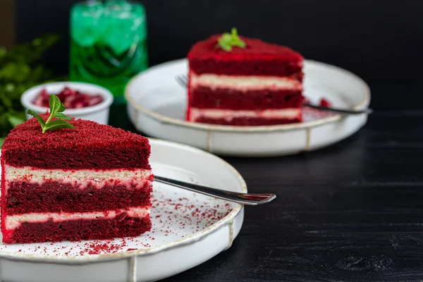 Cake Red velvet on two white plates, two servings. On a black background. Birthday, holidays, sweets. Copy space