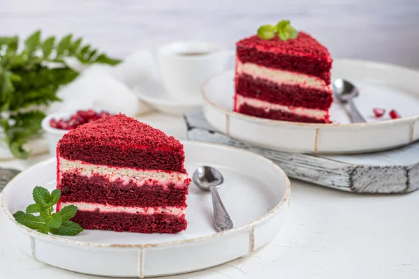 İki beyaz tabakta kırmızı kadife kek, iki porsiyon. Hafif bir arkaplanda. Doğum günü, tatiller, şekerler. Boşluğu kopyala